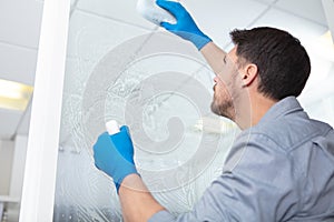 male worker cleaning glass window with sponge