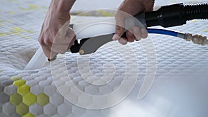 Male Worker Cleaning a mattress With Vacuum Cleaner.Professionally extraction method. Upholstered furniture. Mattress