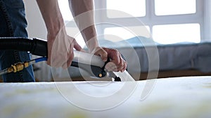 Male Worker Cleaning a mattress With Vacuum Cleaner.Professionally extraction method. Upholstered furniture. Mattress