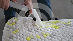 Male Worker Cleaning a mattress With Vacuum Cleaner.Professionally extraction method. Upholstered furniture. Mattress