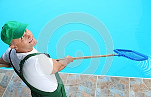 Male worker cleaning outdoor pool with net