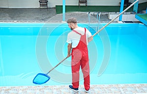Male worker cleaning outdoor pool with net