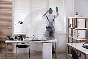 Male Worker Cleaning Window Blinds With Sponge