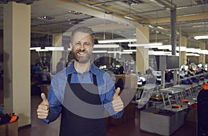 Male worker of clothing and footwear factory showing cool gesture guaranteeing product quality.