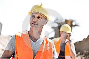 Male worker at construction site with colleague standing in background