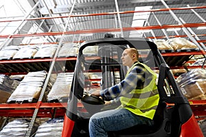 Male worker driving forklift loader at warehouse