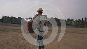 Male worker in exoskeleton carrying barrel