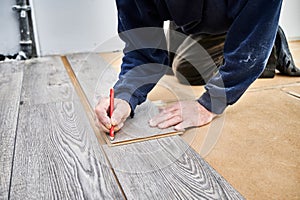 Male worker hands drawing line on laminate panel.