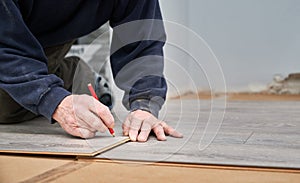 Male worker hands drawing line on laminate panel.