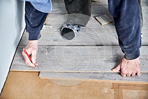 Male worker hands drawing mark on laminate plank.