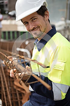 male worker holding metal reinforcing bar structure