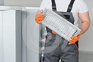 A male worker holds an air filter for air conditioning in an office space. Installation of an air conditioner.