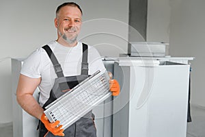 A male worker holds an air filter for air conditioning in an office space. Installation of an air conditioner.