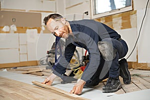 A Male Worker install wood floor on a house