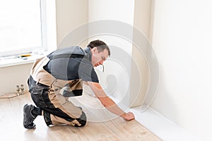 Male worker installing new wooden laminate flooring on a warm film foil floor. infrared floor heating system under