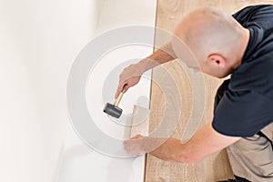Male worker installing new wooden laminate flooring on a warm film foil floor. infrared floor heating system under