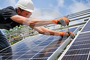Male worker installing photovoltaic solar panel outdoors.
