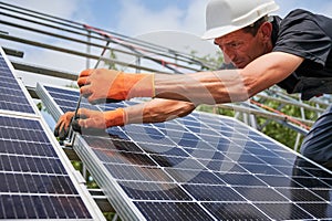 Male worker installing photovoltaic solar panel outdoors.