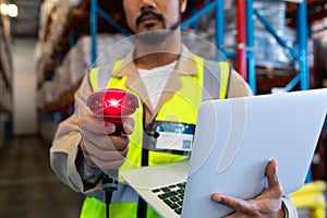 Male worker with laptop showing barcode scanner on camera in warehouse