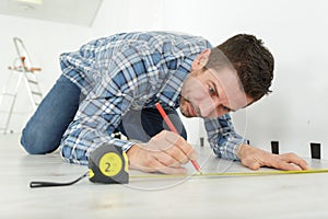 male worker makes measurements and installing new wooden laminate flooring