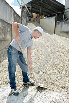 male worker mixing cement and pebbles together with shovel