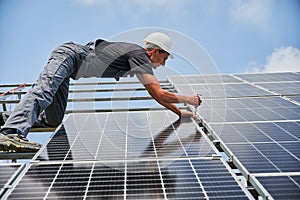 Male worker mounting photovoltaic solar panel system outdoors.