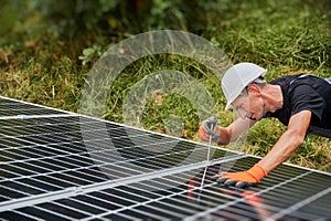 Male worker mounting photovoltaic solar panel system outdoors.