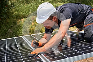 Male worker mounting photovoltaic solar panel system outdoors.