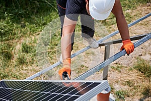 Male worker mounting photovoltaic solar panel system outdoors.