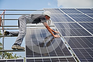 Male worker mounting photovoltaic solar panel system outdoors.