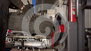 Male worker mounting tire on wheel rim using special machine.