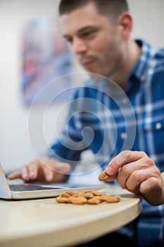 Male Worker In Office Having Healthy Snack Of Nuts