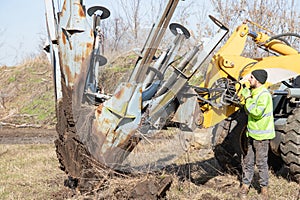 Male worker operates tree transplanter heavy machine. Landscaping, seasonal agricultural engineering, large trees landing machines