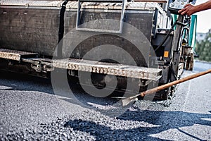 Male worker operating asphalt paver machinery