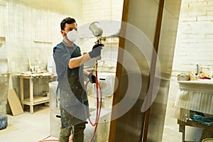 Male worker painting a brown door in a woodshop photo