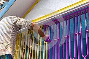 Male worker painting purple paint on iron door