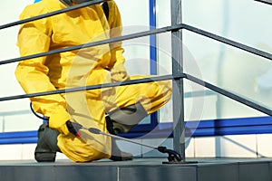 Male worker in protective suit spraying insecticide on stairs outdoors. Pest control