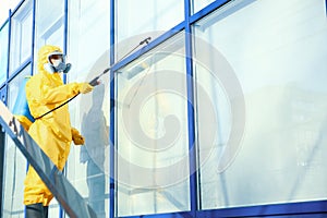 Male worker in protective suit spraying insecticide on window, space for text. Pest control