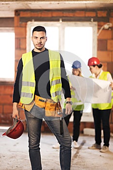 Male worker on a residential construction site with his team of engineers working in the background