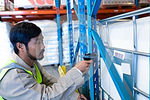 Male worker scanning package with barcode scanner in modern warehouse