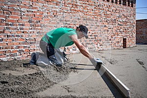 Male worker screeding floor at construction site.