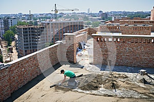 Male worker screeding floor outdoors at construction site.