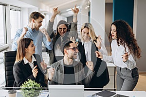 Male worker share good news with multiracial colleagues in shared workplace, diverse employees scream with happiness excited with