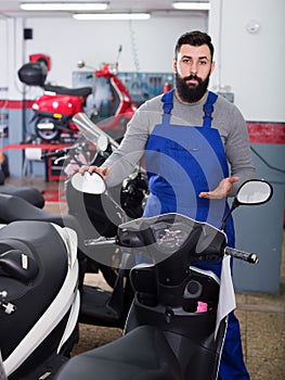 Male worker showing scooters in motorcycle workshop