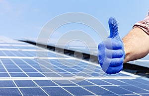 Male worker showing thumbs up, positive gesture against solar panel, solar station. Like to alternative energy sun energy power.