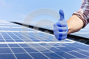Male worker showing thumbs up, positive gesture against solar panel, solar station. Like to alternative energy sun energy power.