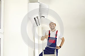 Male worker showing thumbs up after repairing or installing wall air conditioner