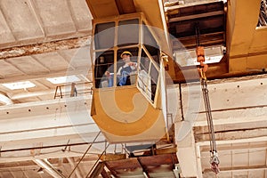 Male worker sitting in operator cabin of overhead crane