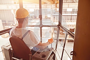 Male worker sitting in operator cabin of overhead crane