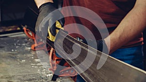 Male worker of ski service workshop doing sharpening and repair of skis. Sharpening ski edges with a manual side-edge tuning tool